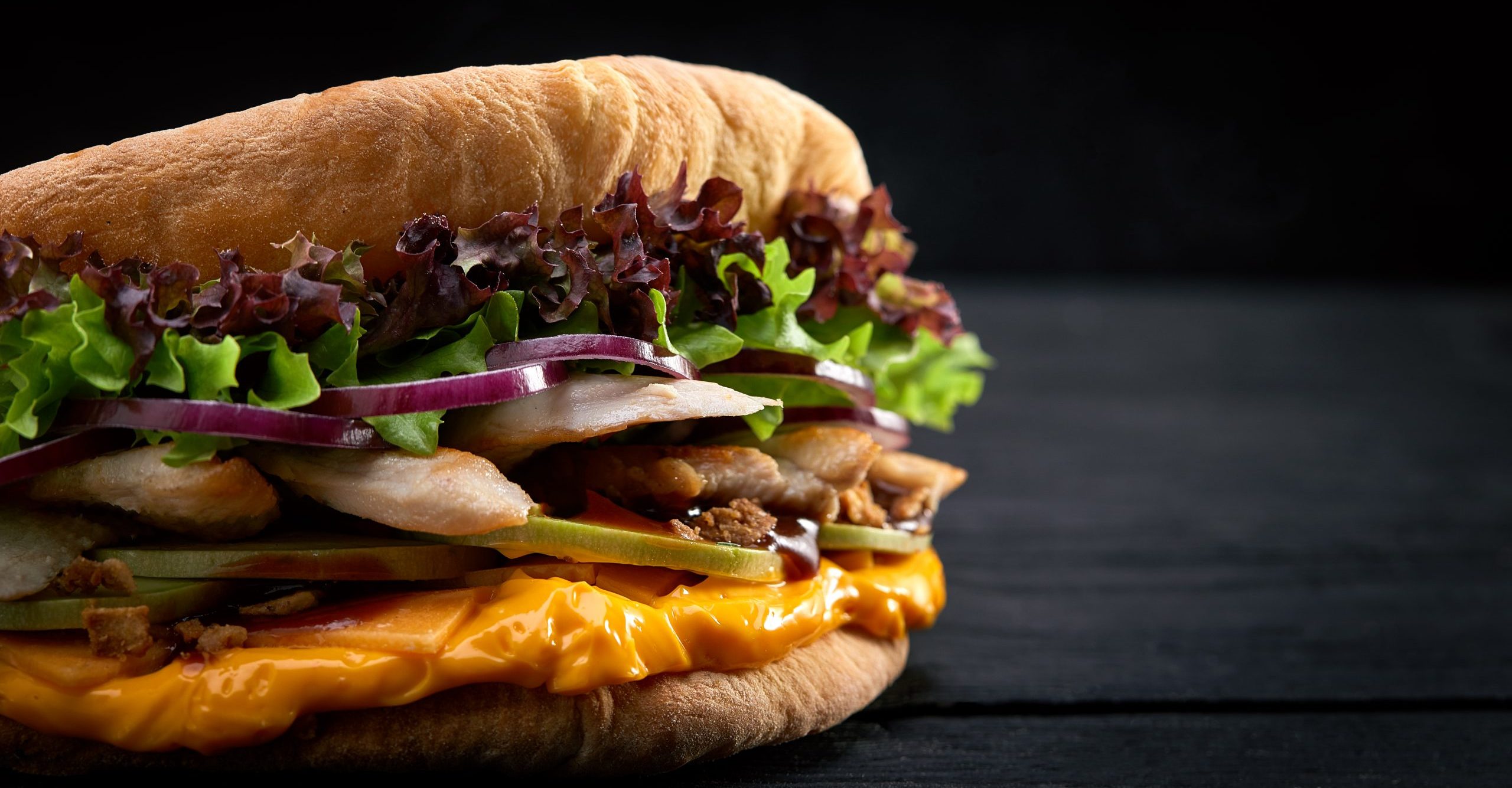 Doner kebab - fried chicken meat with vegetables in pita bread on black wooden background